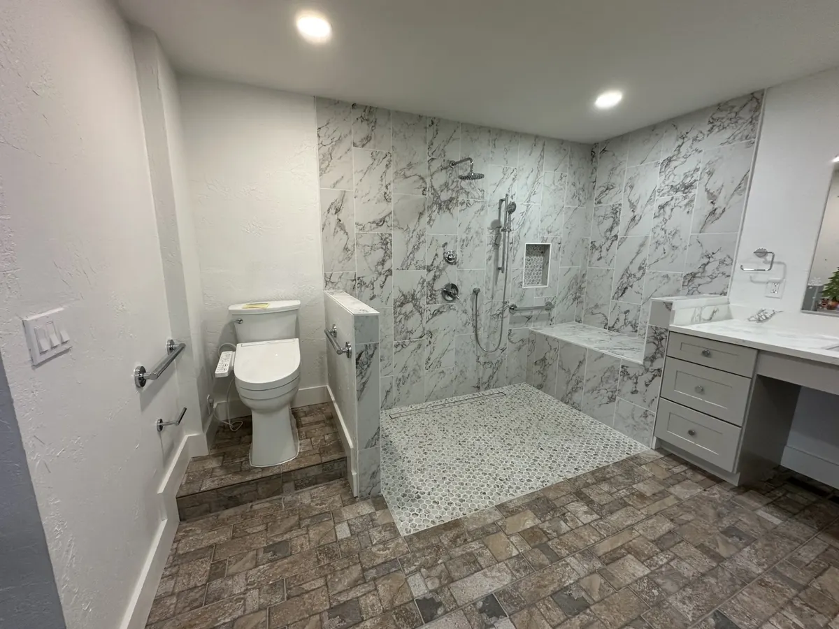 Accessible bathroom with a curbless marble-look shower, grab bars, and a bench
