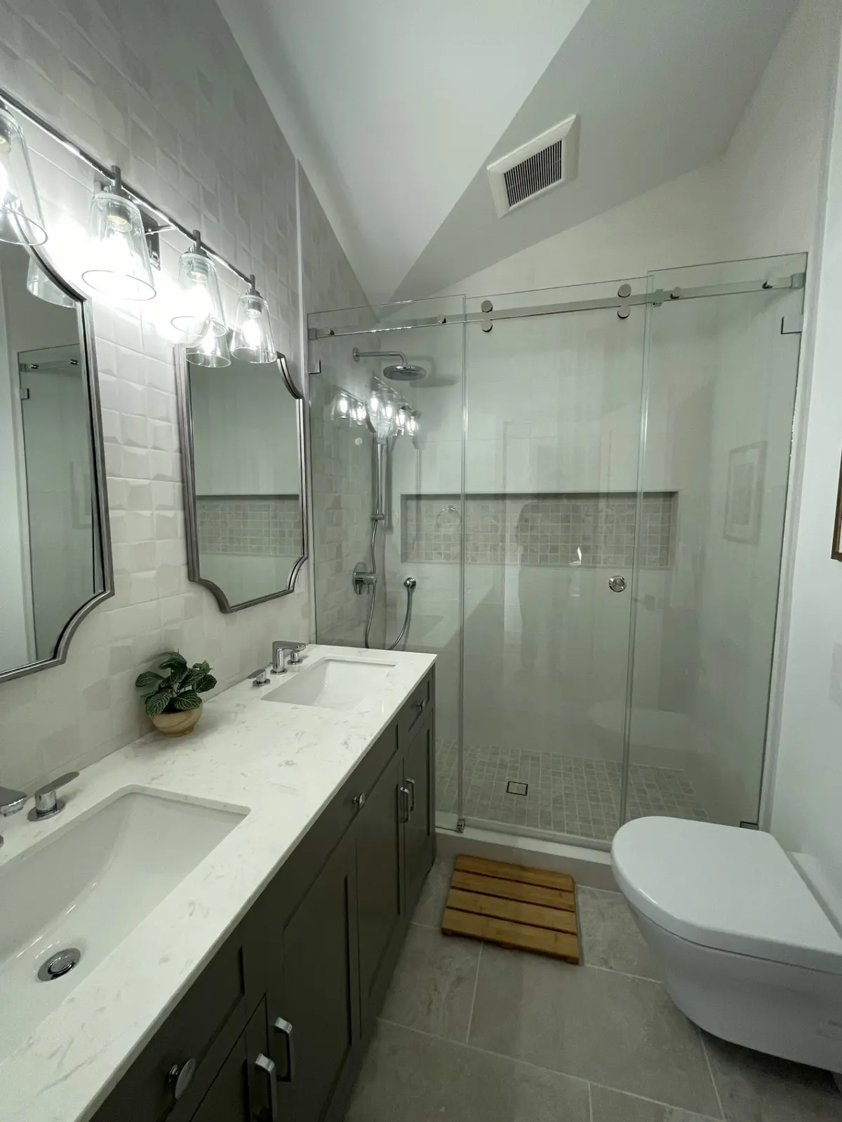 Bathroom with a sliding glass shower door, double mirrors, and a white vanity