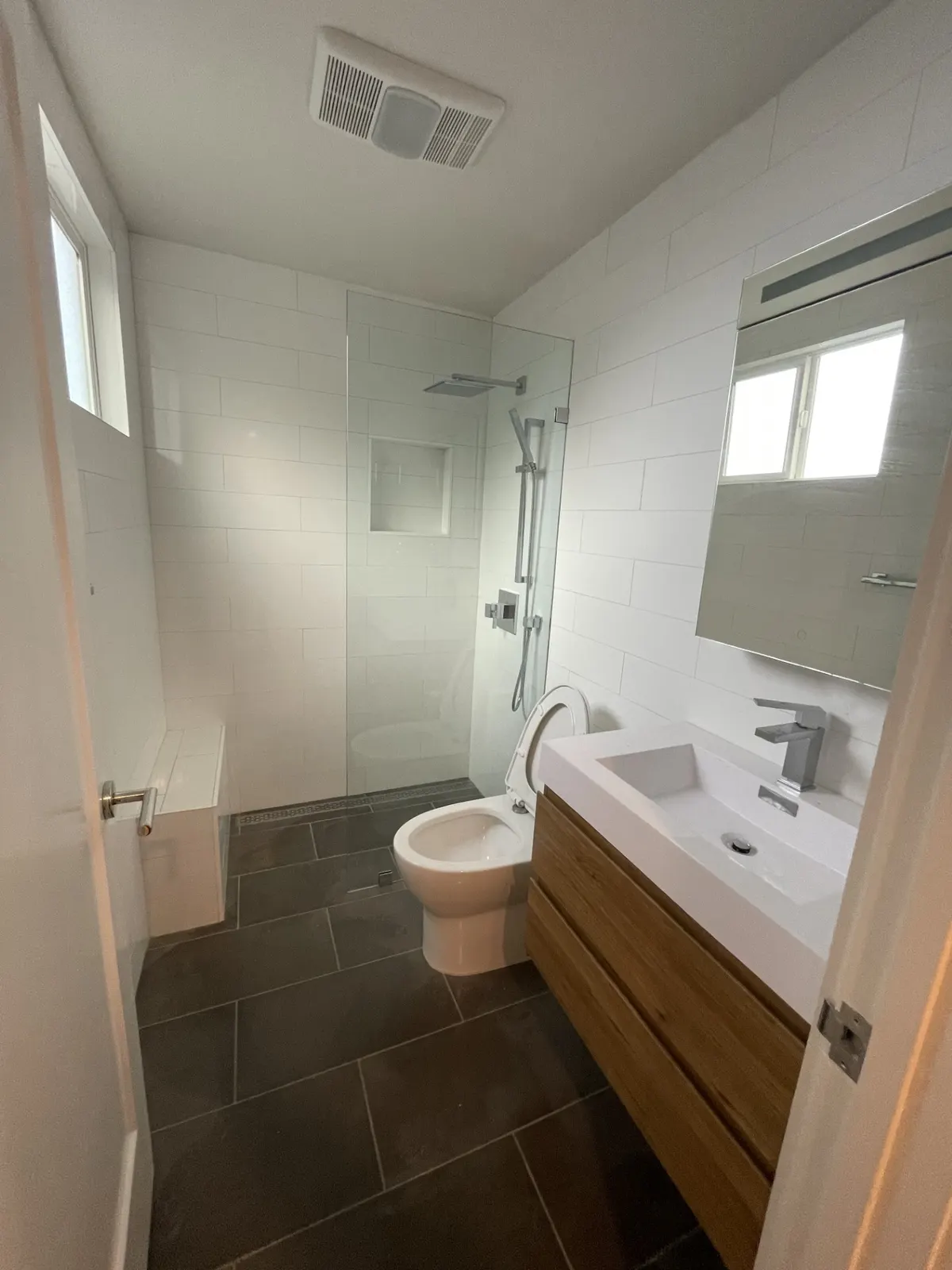 Bathroom with a walk-in shower, wood vanity, and dark tile floor
