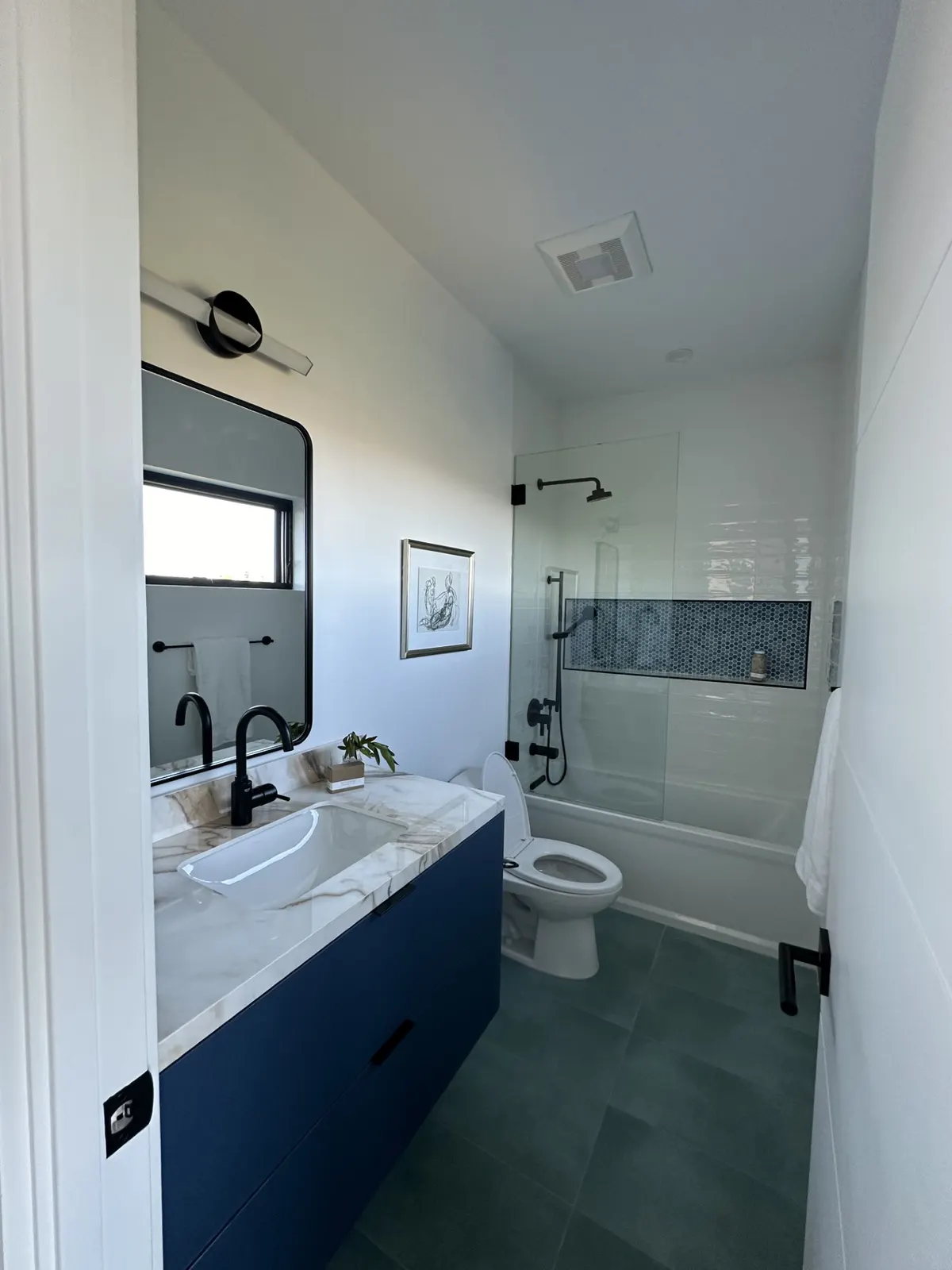 Bathroom with a blue vanity, black fixtures, and a tiled tub shower
