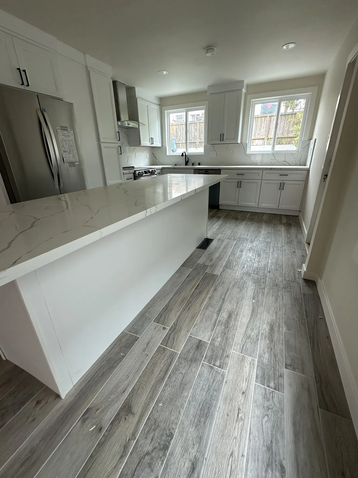 Renovated kitchen with white cabinets, quartz counters, and wood-look floors