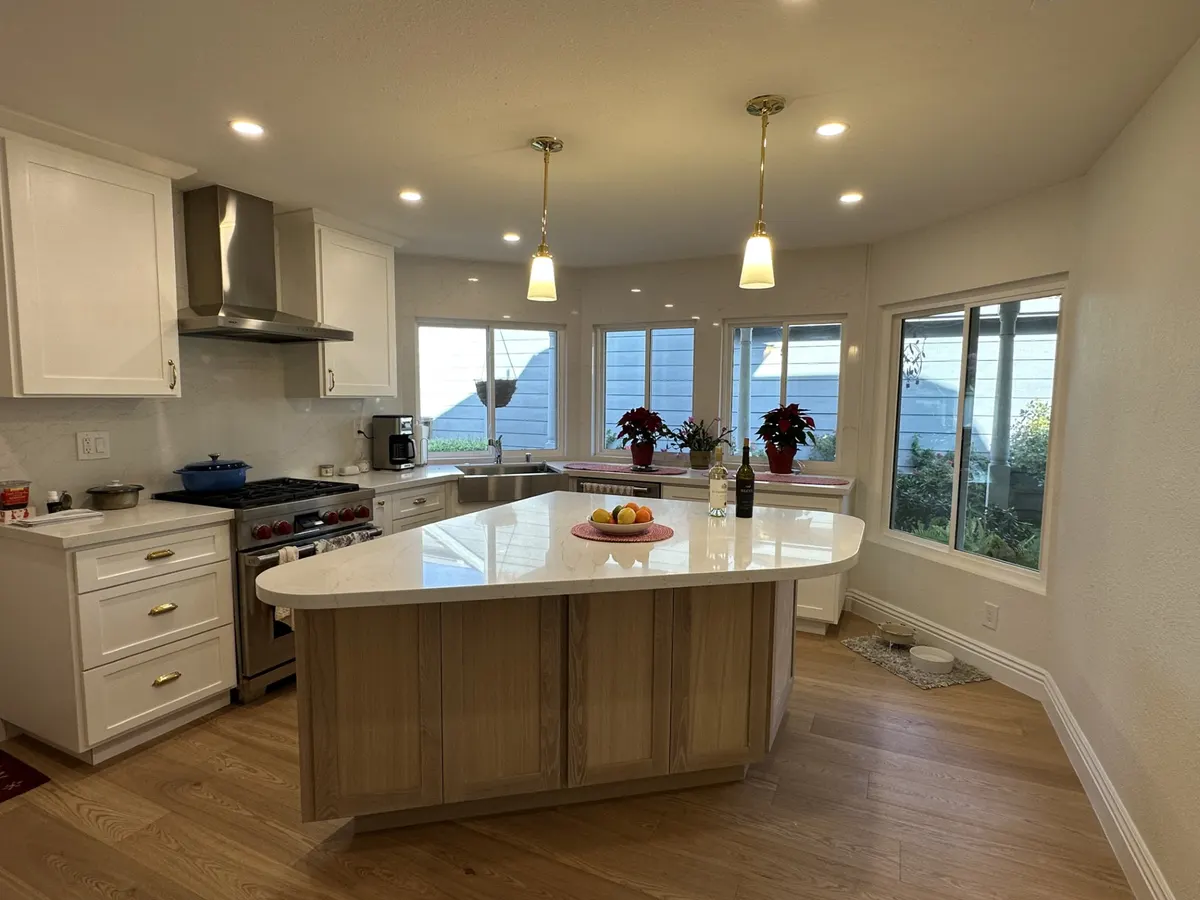 Kitchen with a curved white quartz island, oak cabinets, and pendant lights