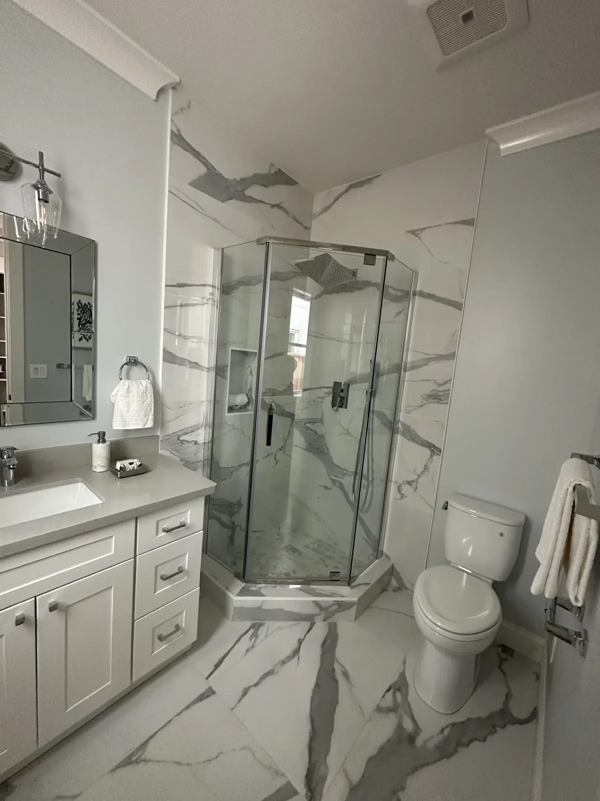 Bathroom with marble-look tile, a corner glass shower, and a white vanity