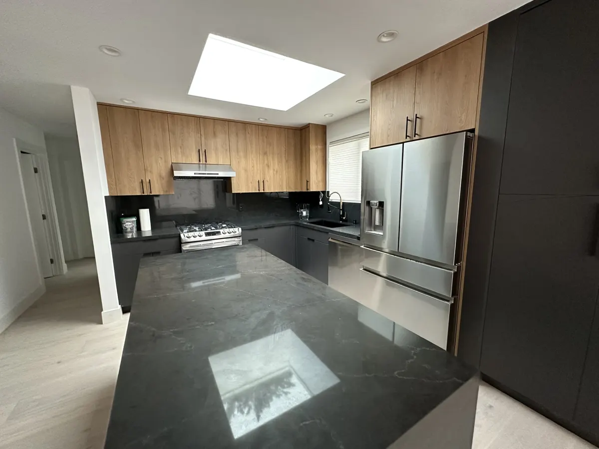 Modern kitchen with a black island, wood upper cabinets, and a skylight