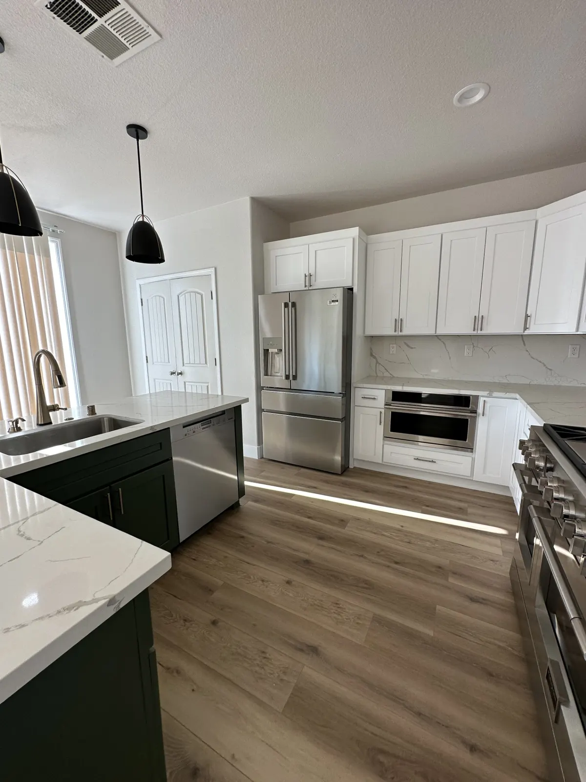 White kitchen with marble-look backsplash, a gas range, and pendant lights