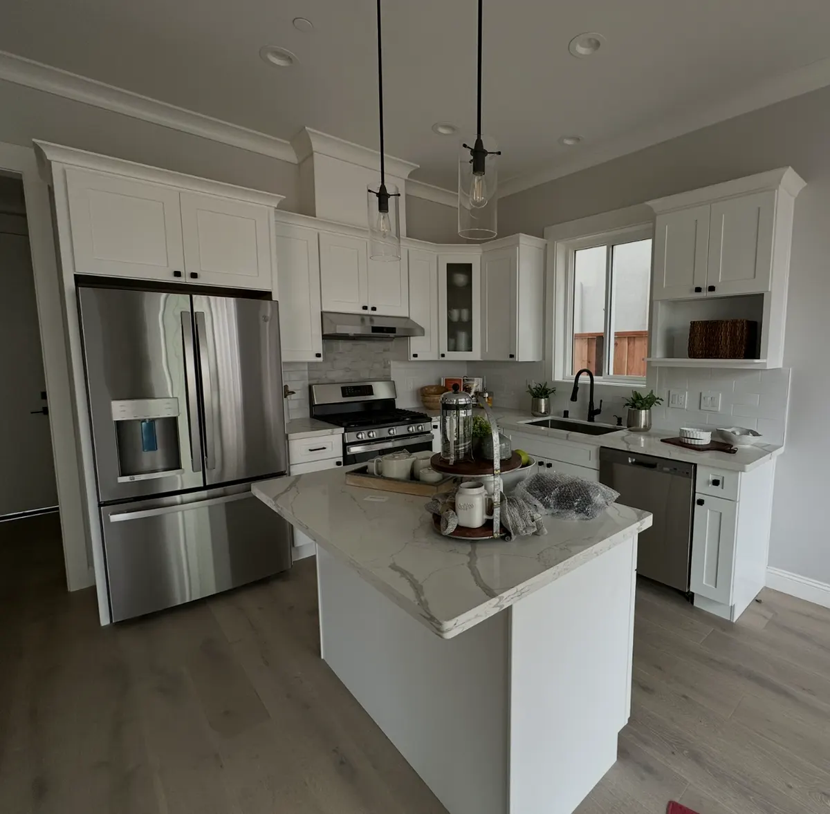 White kitchen with an island, pendant lights, and stainless appliances